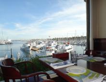 Photo of 22nd Street Landing Seafood Grill & Bar with view across a table set for dining through windows to boats in the marina
